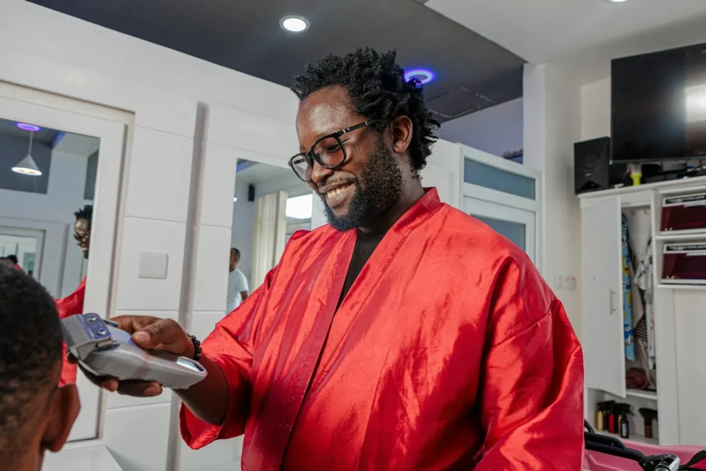 Barber in a red gown trimming a client's hair