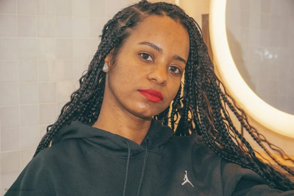 Woman with long box braids in a salon by a ring light