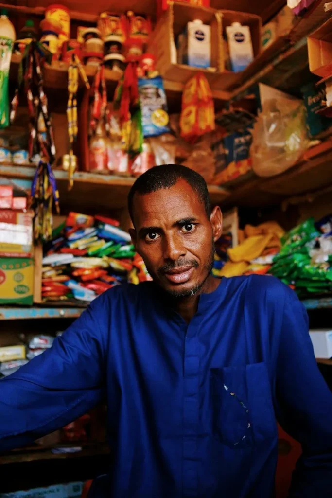 Shop owner standing in front of shelves of goods in his store