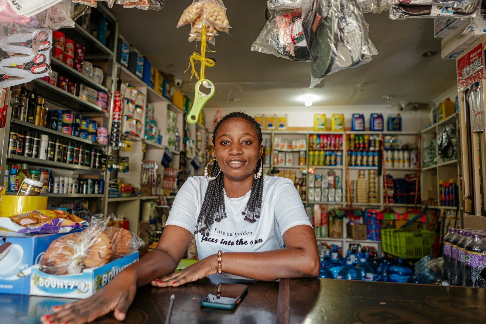 Smiling shop owner behind the counter of her well-stocked convenience store