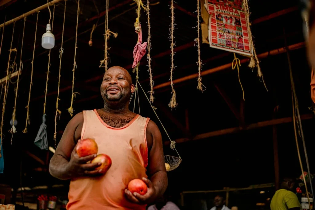 Market trader holding fresh tomatoes at his produce stall