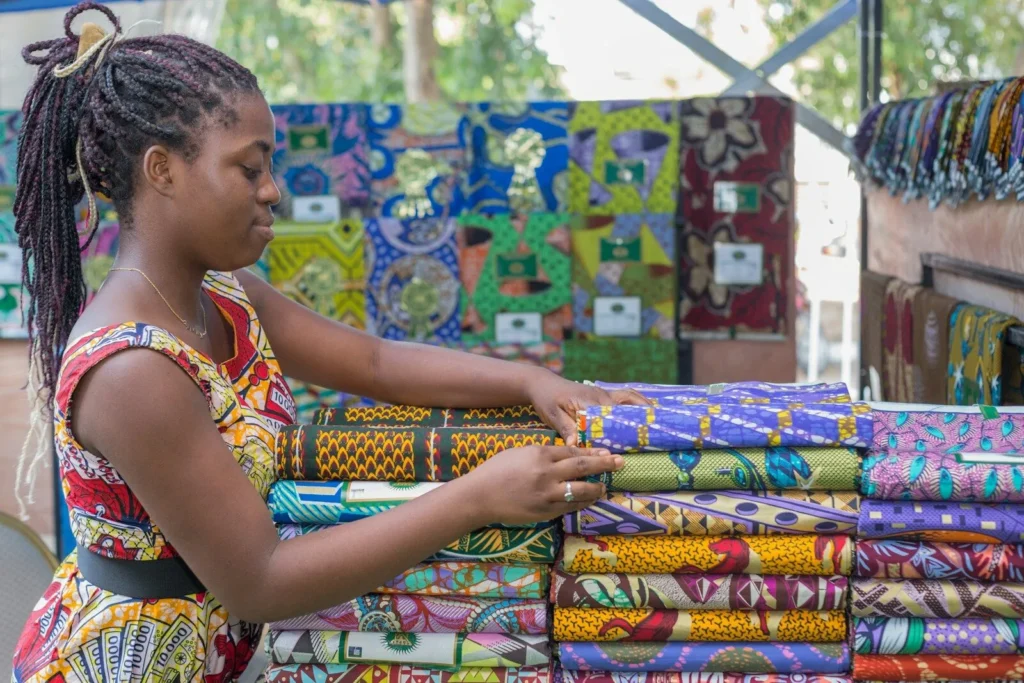 Fabric trader arranging colourful wax-print cloth on her stall