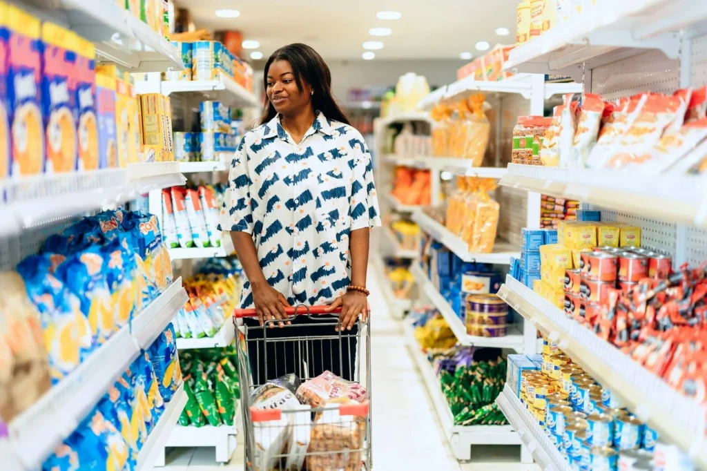 Woman pushing a trolley down a well-stocked grocery aisle